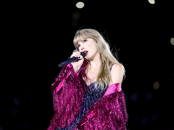 Woman in vintage-inspired, whimsical Magnolia Pearl artisan clothing with sparkly magenta fringe, performing on stage